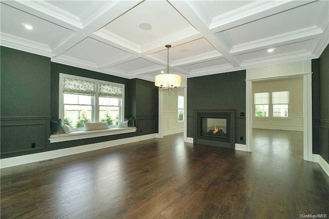 unfurnished living room with an inviting chandelier, beamed ceiling, a healthy amount of sunlight, and coffered ceiling