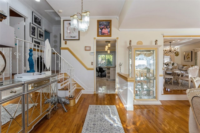 entrance foyer with crown molding, hardwood / wood-style floors, and a chandelier