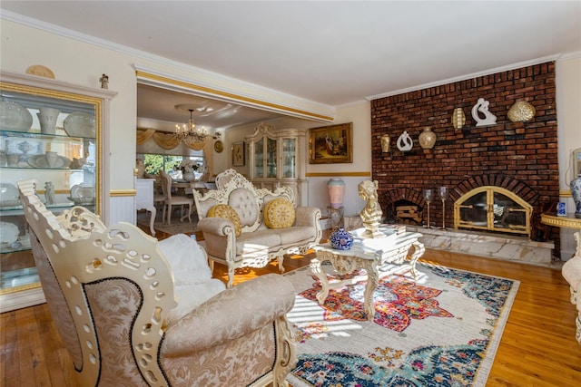 living room with an inviting chandelier, hardwood / wood-style flooring, a brick fireplace, and crown molding