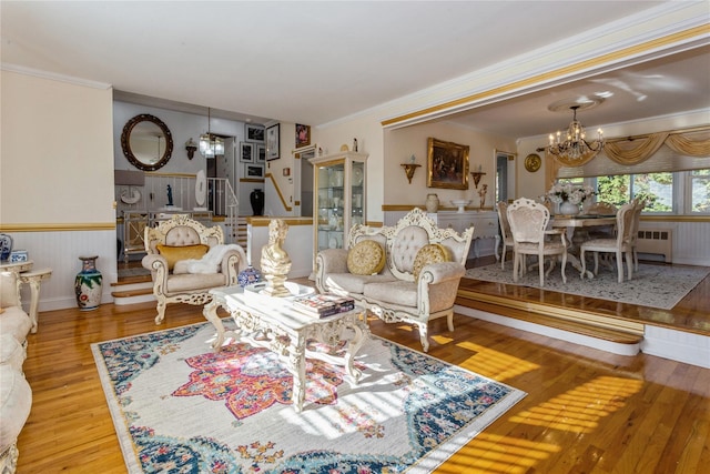 living room with a chandelier, light wood-type flooring, and ornamental molding