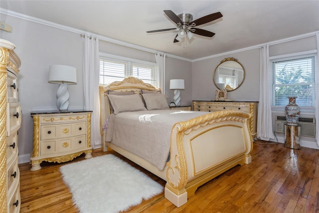 bedroom with wood-type flooring, a wall unit AC, ceiling fan, and ornamental molding