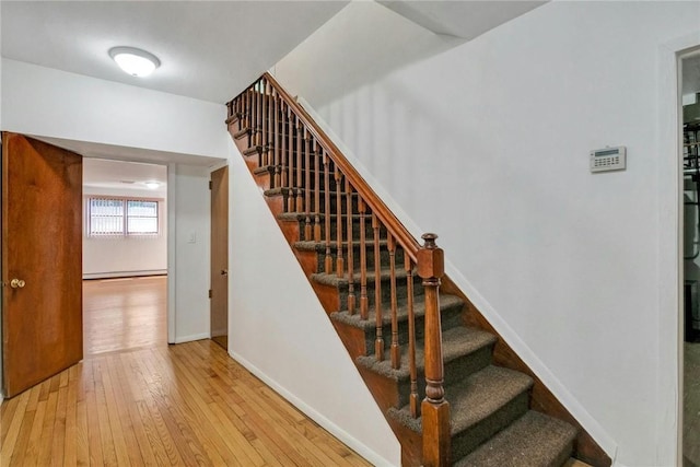 staircase with hardwood / wood-style flooring and a baseboard heating unit