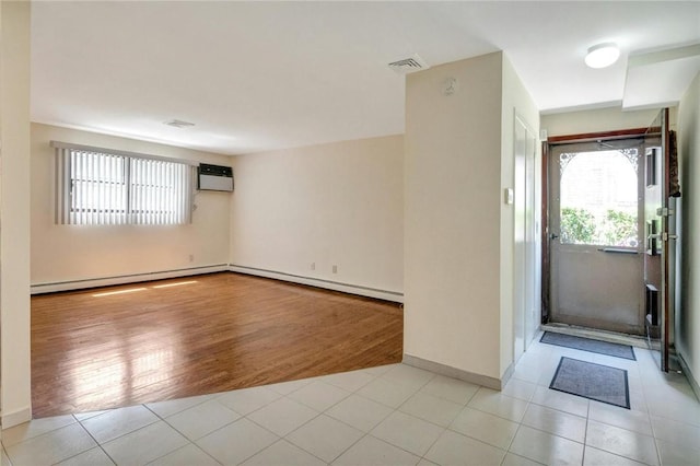 empty room with a wall mounted air conditioner, light hardwood / wood-style floors, and baseboard heating