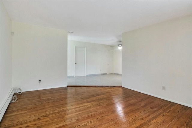 spare room featuring hardwood / wood-style floors, ceiling fan, and baseboard heating