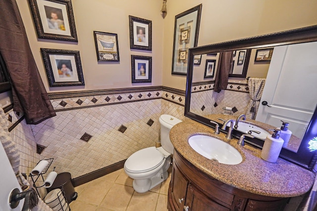 bathroom with tile patterned flooring, vanity, toilet, and tile walls