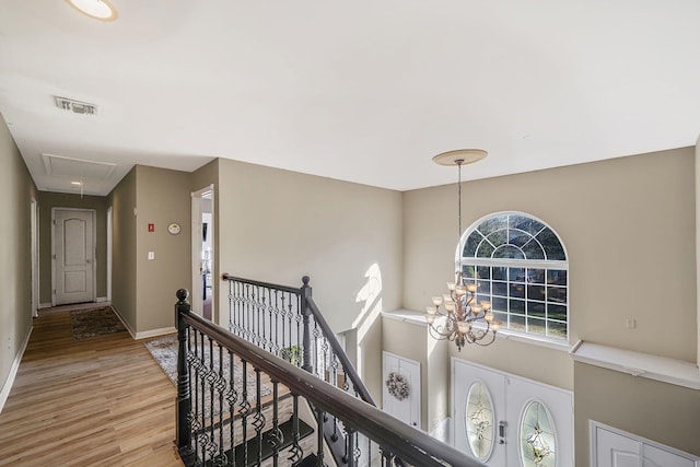 corridor with hardwood / wood-style flooring and a notable chandelier