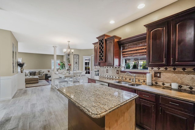 kitchen with sink, hanging light fixtures, light wood-type flooring, tasteful backsplash, and a kitchen island