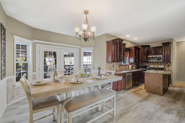 kitchen with french doors, light hardwood / wood-style flooring, decorative light fixtures, and appliances with stainless steel finishes