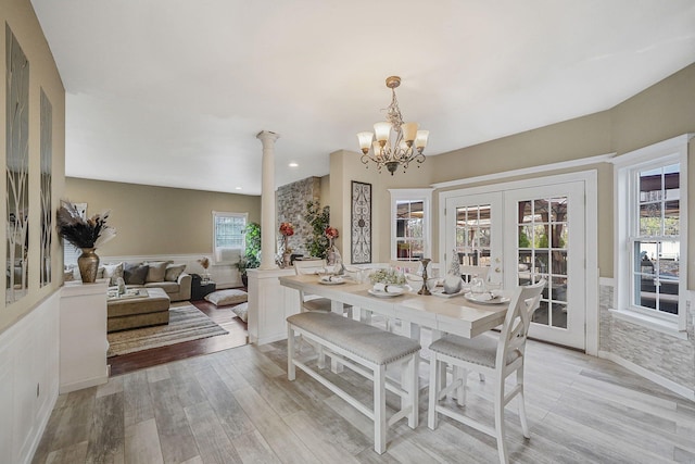 dining room featuring french doors, an inviting chandelier, decorative columns, and light hardwood / wood-style flooring