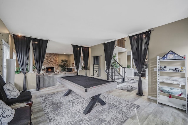 game room featuring light hardwood / wood-style floors, a fireplace, and pool table