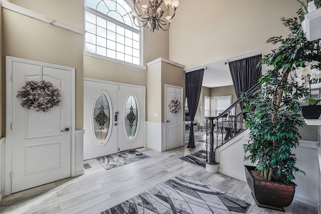 entryway with light wood-type flooring, a high ceiling, a wealth of natural light, and french doors