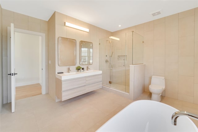 full bathroom with tile walls, toilet, tile patterned floors, independent shower and bath, and vanity