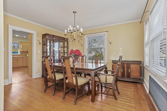 dining room featuring radiator, an inviting chandelier, ornamental molding, and light hardwood / wood-style floors