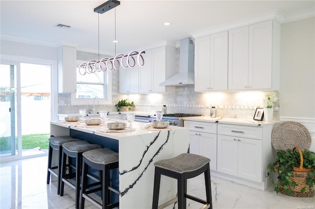 kitchen featuring white cabinets, wall chimney exhaust hood, and decorative light fixtures