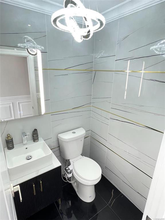 bathroom with tile patterned floors, vanity, toilet, and crown molding