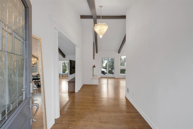 foyer featuring beam ceiling, a healthy amount of sunlight, a chandelier, and wood-type flooring