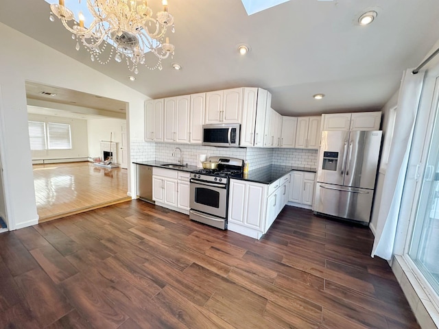 kitchen with stainless steel appliances, dark hardwood / wood-style floors, vaulted ceiling, decorative light fixtures, and white cabinets