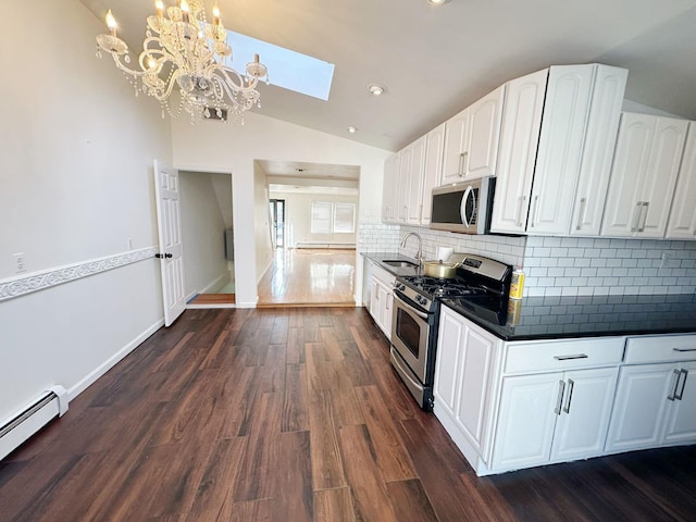 kitchen with pendant lighting, lofted ceiling with skylight, dark wood-type flooring, white cabinets, and appliances with stainless steel finishes