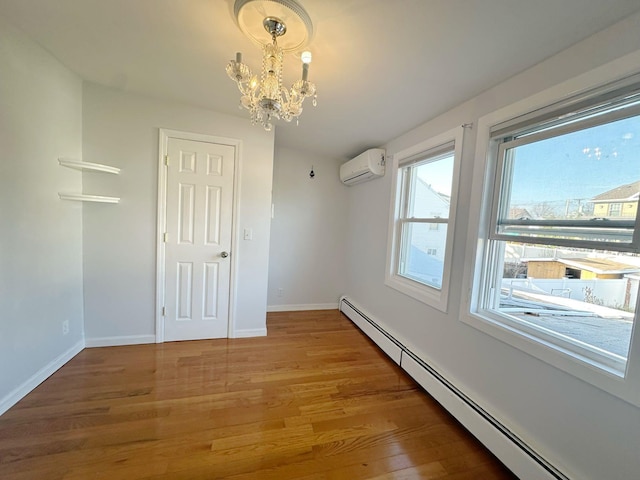 empty room featuring hardwood / wood-style floors, a notable chandelier, an AC wall unit, and baseboard heating