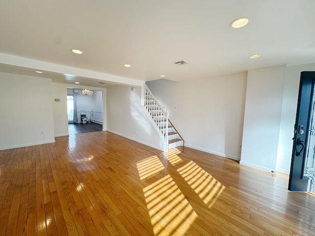 unfurnished living room featuring a chandelier and hardwood / wood-style floors