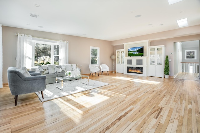 living room featuring a healthy amount of sunlight, light wood-type flooring, and a skylight