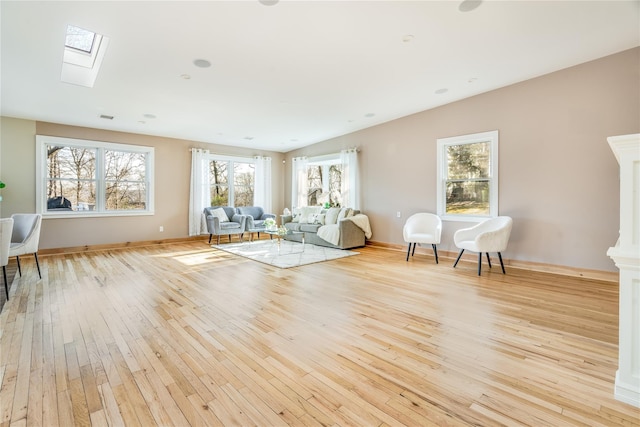 unfurnished room with a skylight and light hardwood / wood-style floors