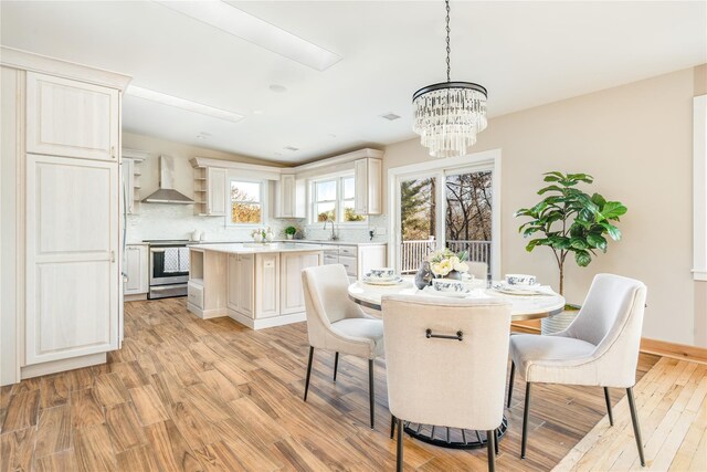 dining room with light wood-type flooring, sink, and a chandelier