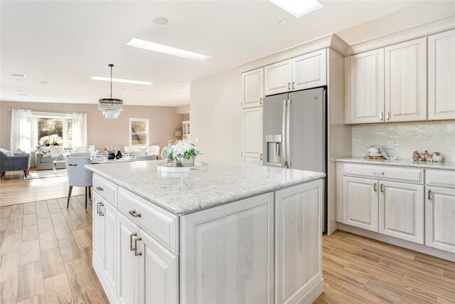 kitchen with white cabinetry, light hardwood / wood-style flooring, a center island, and pendant lighting