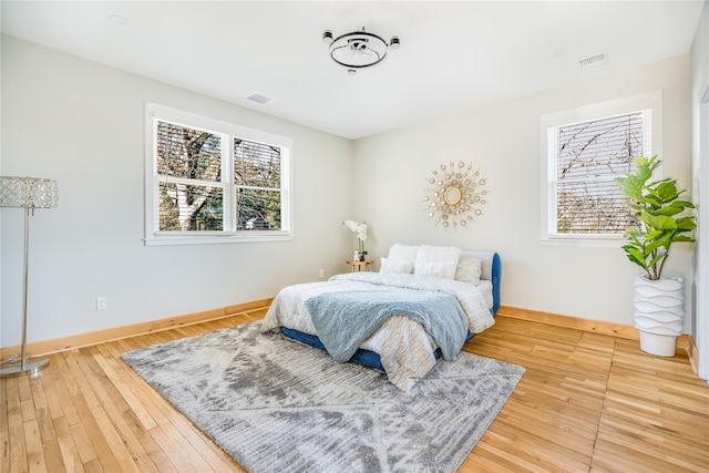 bedroom with hardwood / wood-style flooring and multiple windows