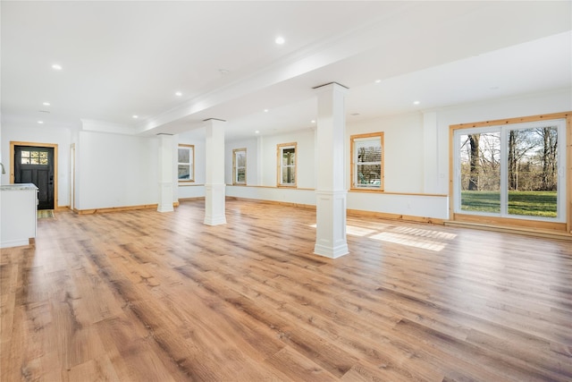 unfurnished living room featuring decorative columns, light hardwood / wood-style flooring, crown molding, and sink