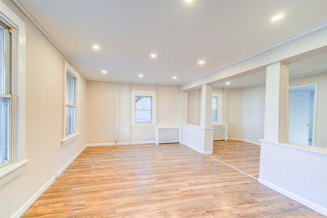 spare room featuring radiator heating unit, light wood-type flooring, and crown molding