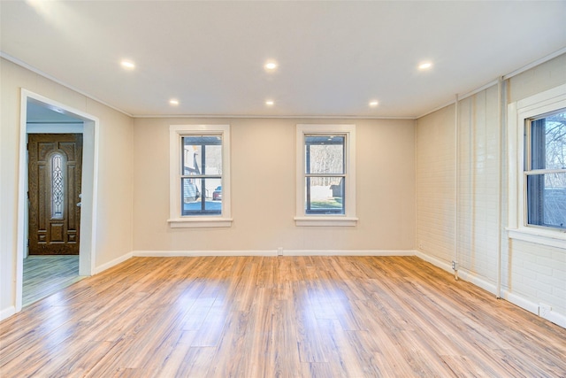 empty room with crown molding and light hardwood / wood-style flooring