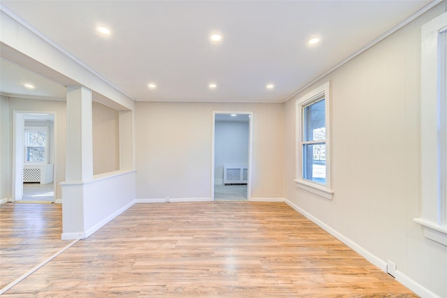 empty room featuring ornamental molding, a healthy amount of sunlight, and light hardwood / wood-style floors