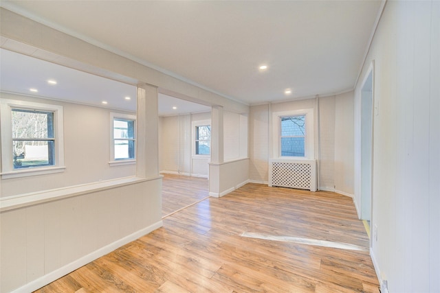 empty room featuring light hardwood / wood-style floors, radiator, and ornamental molding