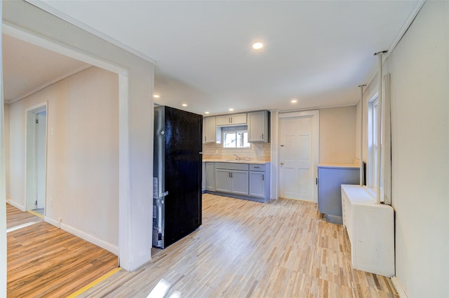 kitchen with black refrigerator, light wood-type flooring, gray cabinets, and tasteful backsplash