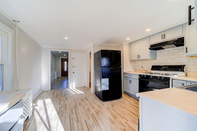 kitchen featuring black refrigerator, decorative backsplash, white gas range, crown molding, and light hardwood / wood-style floors