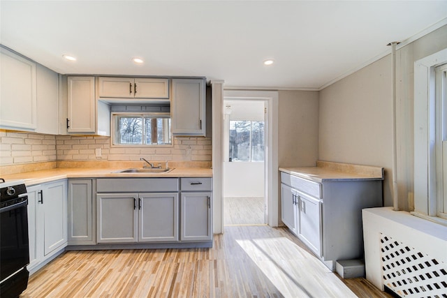 kitchen featuring black electric range, light wood-type flooring, plenty of natural light, and gray cabinetry