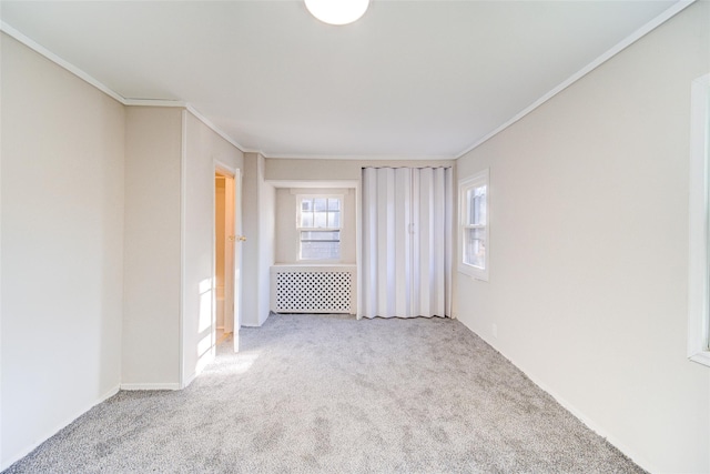 unfurnished room with radiator, crown molding, and light colored carpet