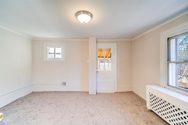 unfurnished room featuring radiator, a wealth of natural light, light carpet, and ornamental molding