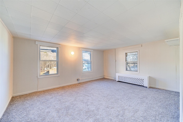 spare room featuring carpet floors, radiator, and a healthy amount of sunlight