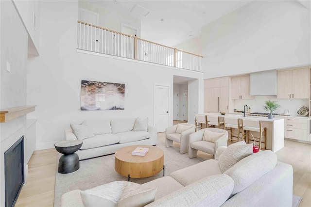 12 Depot Road 1302 (Pearl Way), Westhampton Beach, NY 11978 - living room featuring light wood-style flooring, a high ceiling, a fireplace, and baseboards