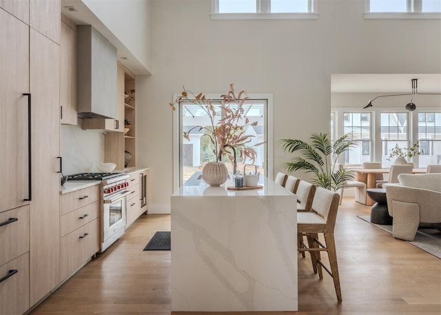 12 Depot Road 1302 (Pearl Way), Westhampton Beach, NY 11978 - kitchen with premium range, a high ceiling, wall chimney range hood, a kitchen breakfast bar, and modern cabinets