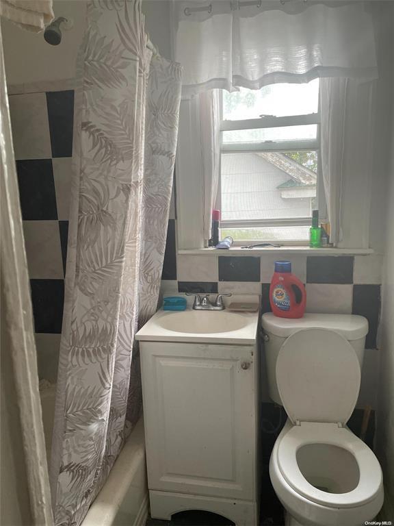 full bathroom with shower / bath combo with shower curtain, vanity, and toilet