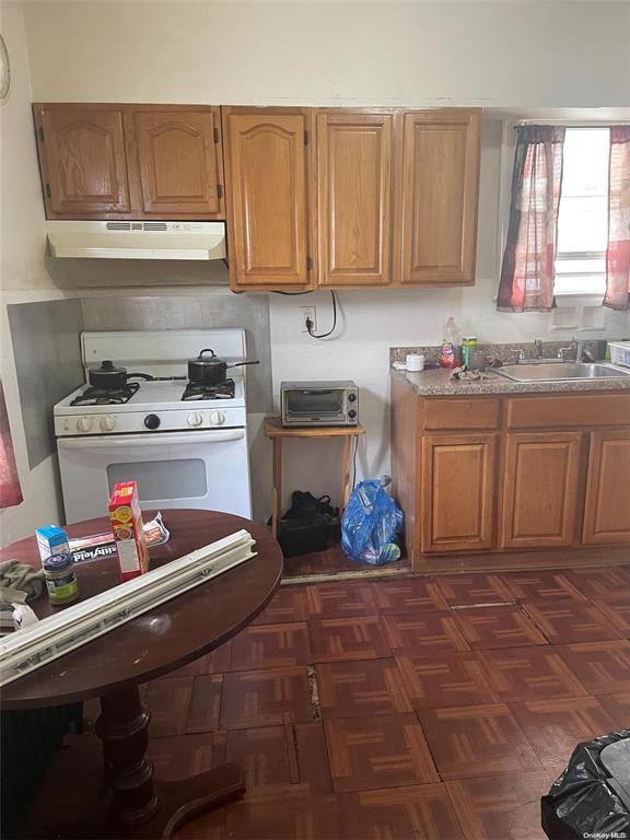 kitchen featuring dark parquet flooring, white range with gas cooktop, and sink