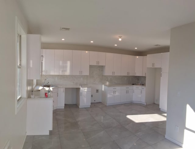 kitchen featuring backsplash, white cabinetry, and sink