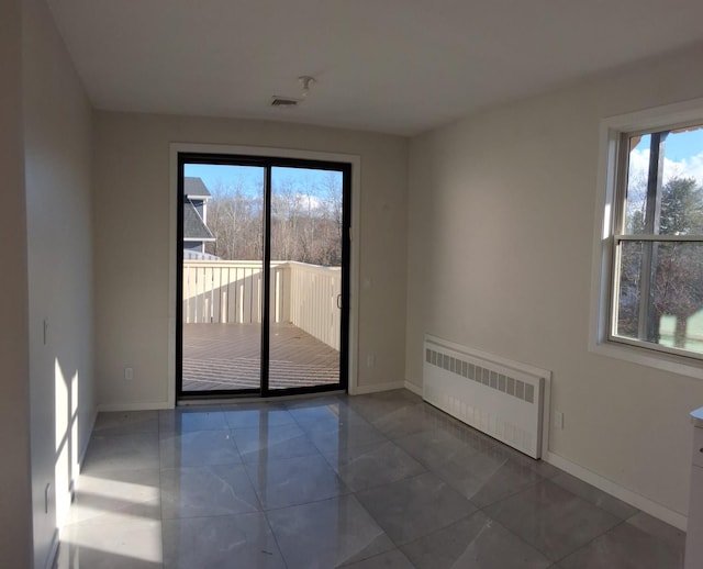 empty room featuring radiator heating unit and a wealth of natural light