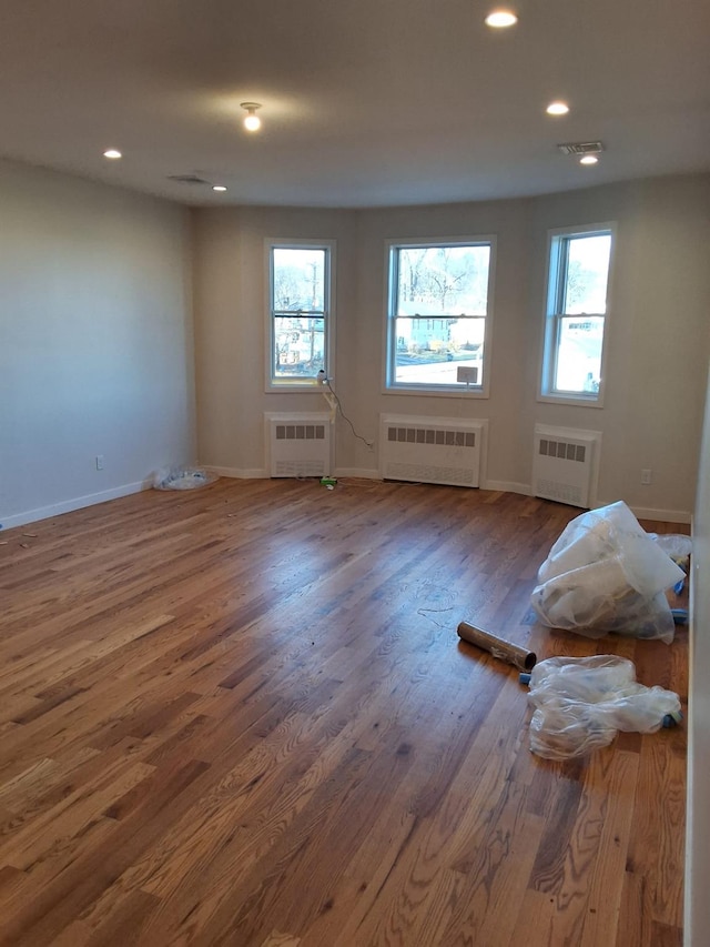 unfurnished room featuring plenty of natural light, dark wood-type flooring, and radiator