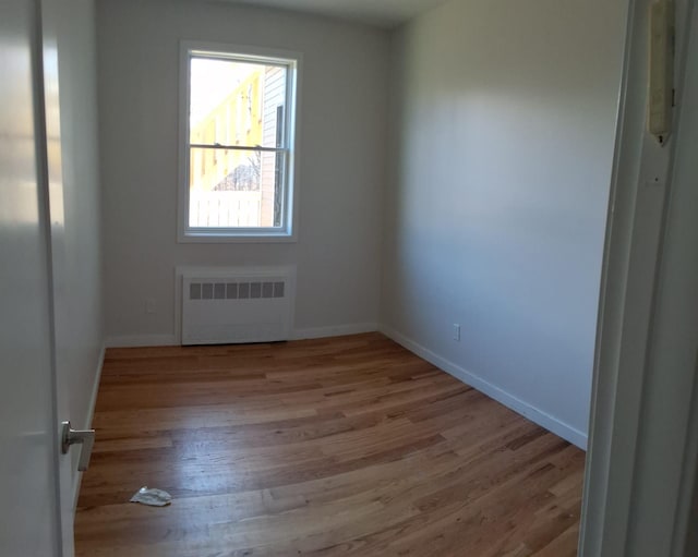 empty room with light hardwood / wood-style flooring and radiator