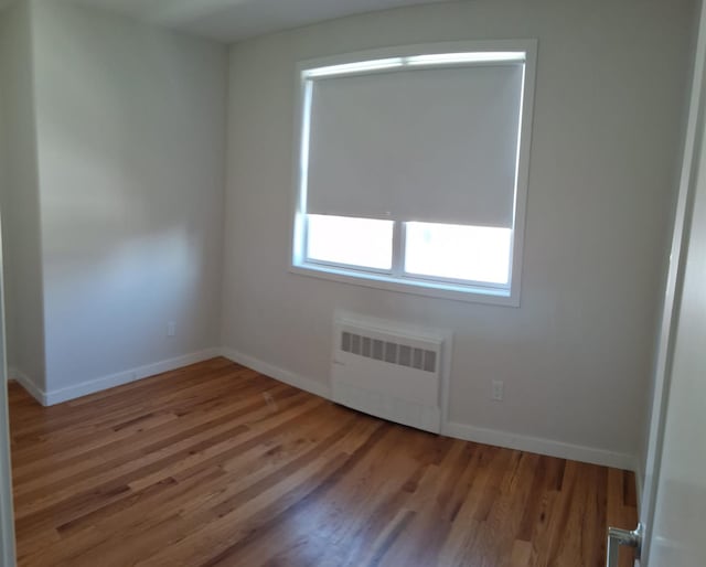 unfurnished room with hardwood / wood-style flooring and radiator