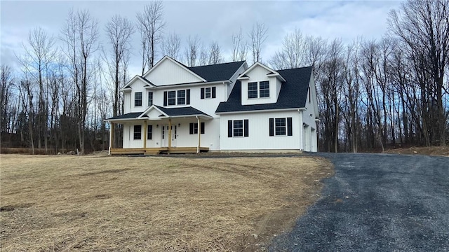 view of front of property featuring a porch, a garage, and a front lawn